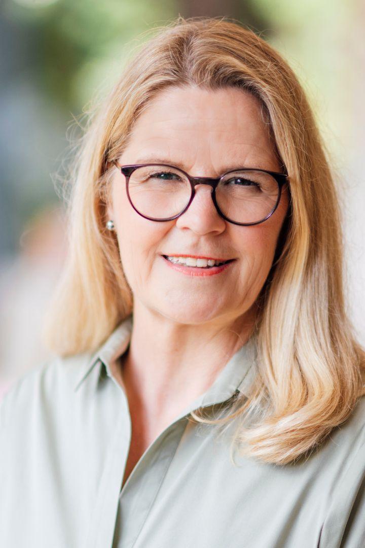 Über Meike Schüttkus, Portrait, hier in pastellgrüner Bluse, blonde lange Haare